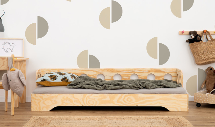 Drewniane łóżko z barierką o okrągłych wycięciach na długim boku wykonane ze sklejki sosnowej w kolorze naturalnego drewna